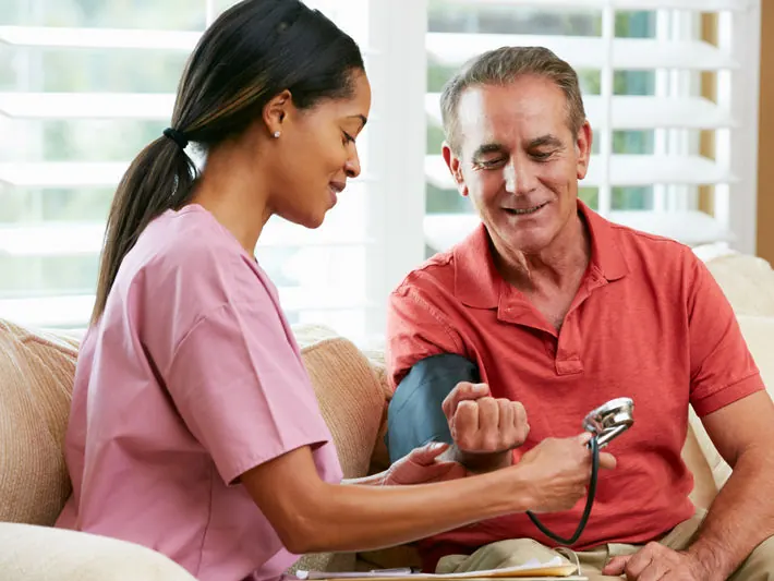 Nurse smiling while caring for a patient in a hospital room