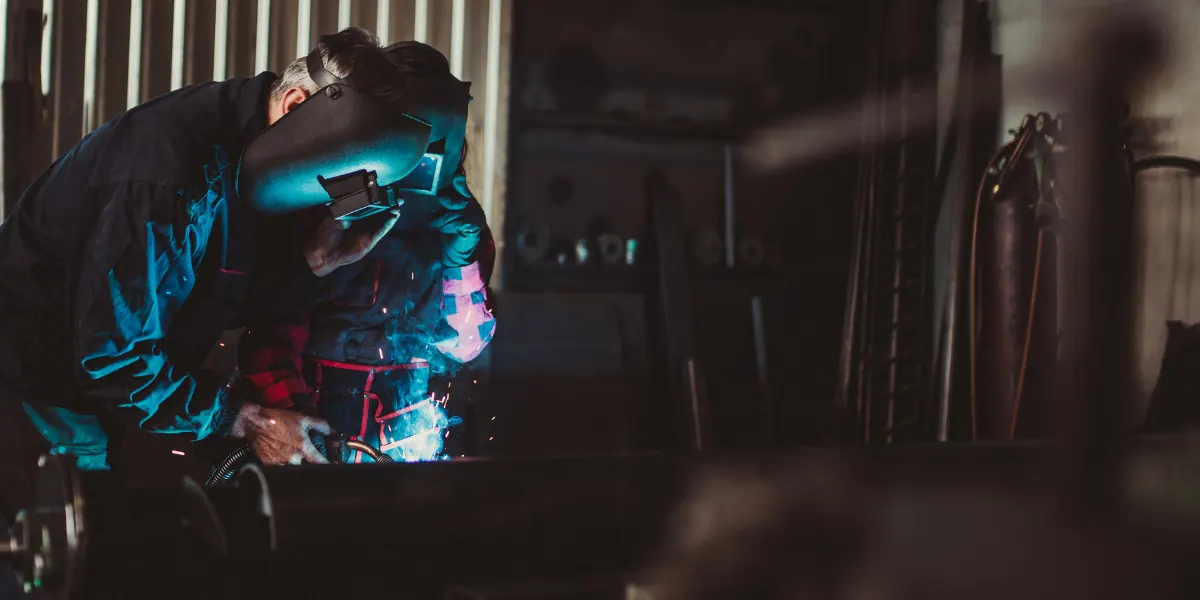 Adult welding student practicing MIG welding in a shop