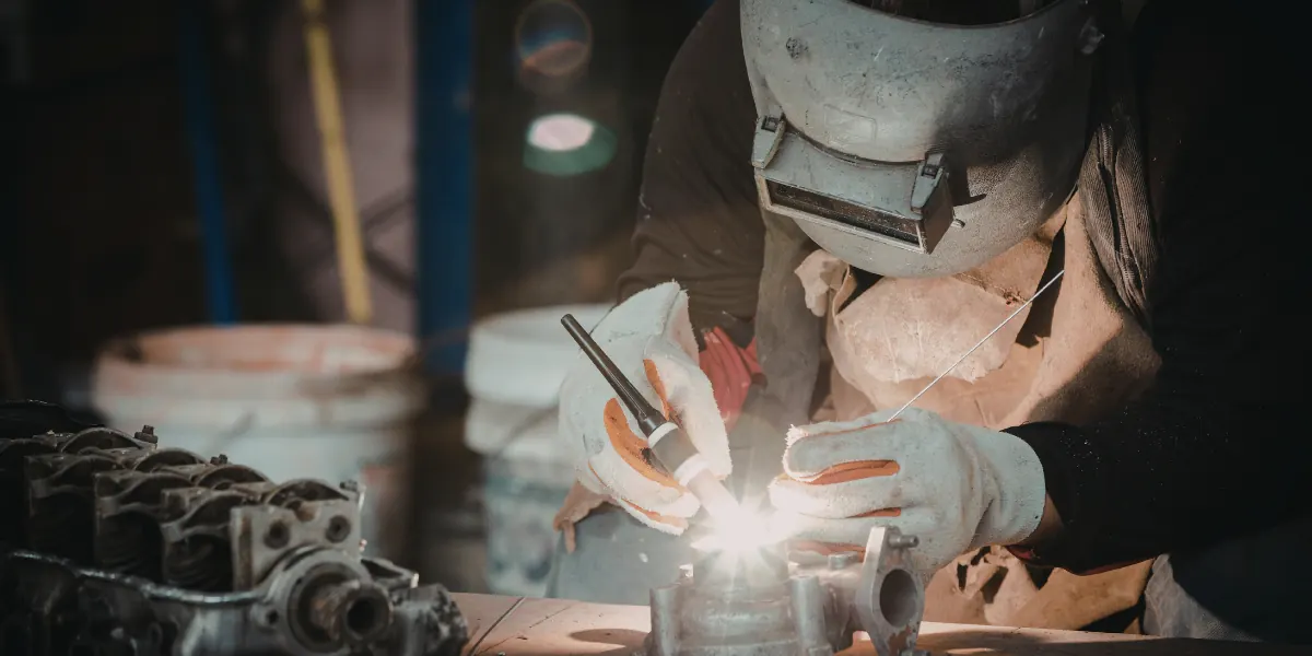 Welding student wearing a protective helmet practicing a weld