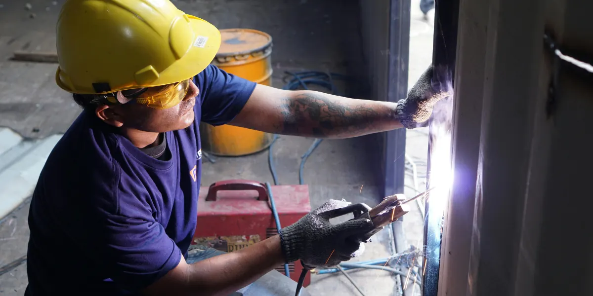 Welding student in protective gear welding a steel joint