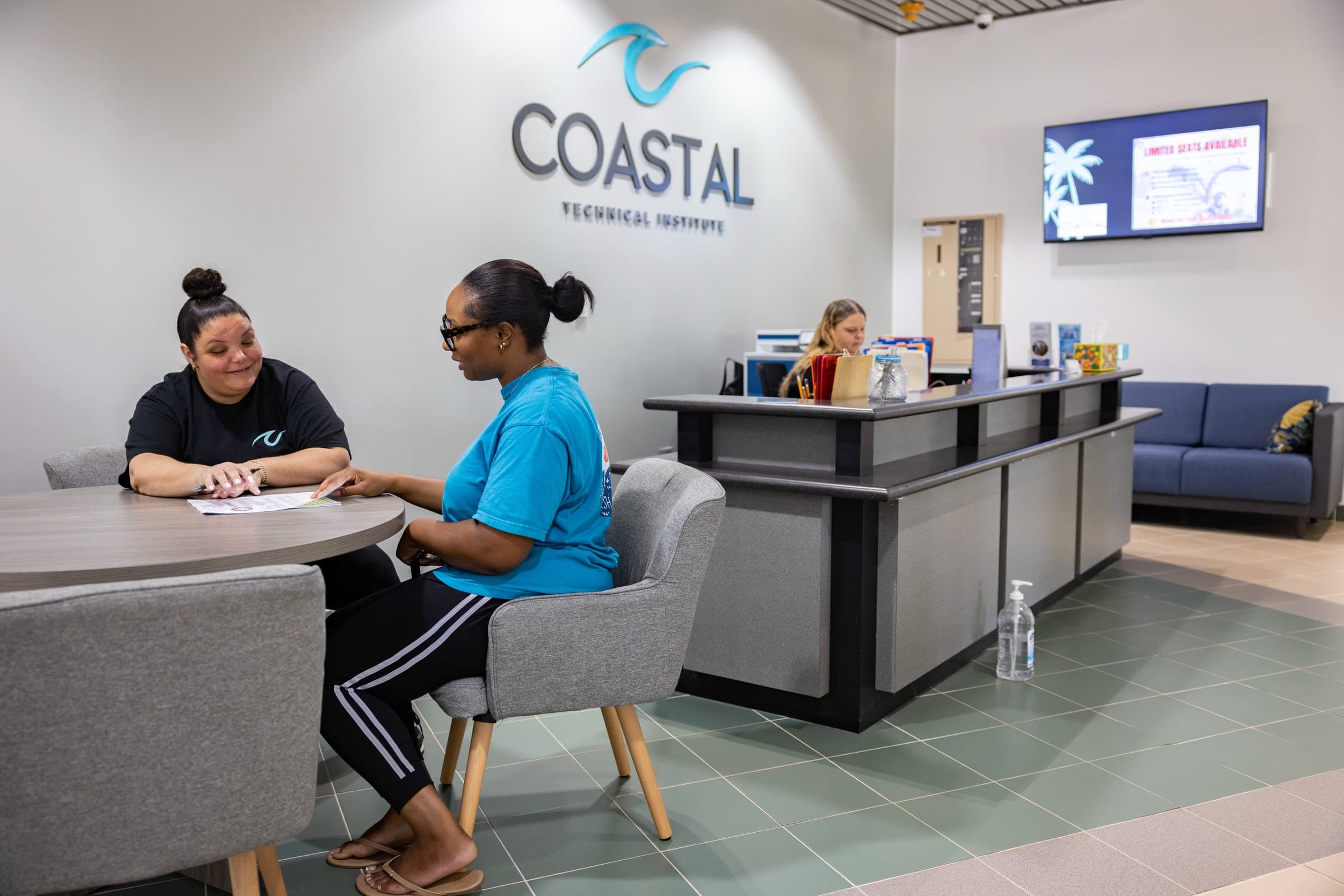 A prospective student meeting with an admissions advisor in the Coastal Technical Institute lobby